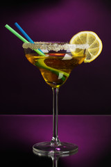 Yellow cocktail in glass on color background