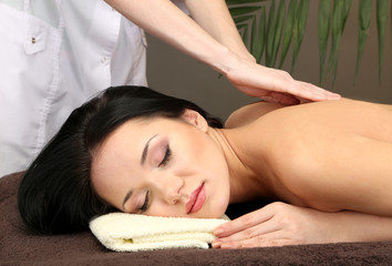 Obraz na płótnie Canvas Beautiful young woman in spa salon getting massage,