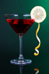 Red cocktail in martini glass on dark green background