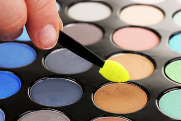 Bright eye shadows and sponge brushes for foundation close up