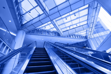 Escalator in modern business center. Blue toning image