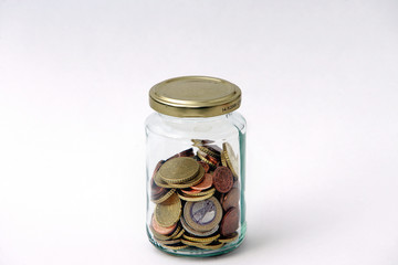 Geldstuecke in einem Glas mit goldenem Deckel.