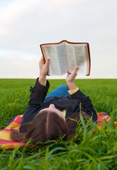 Teen girl reading the Bible outdoors