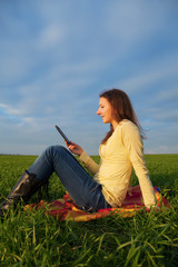 Teen girl reading electronic book outdoors