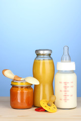 Baby food, bottle of milk, puree and juice on blue background