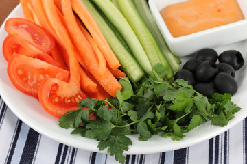 Assorted raw vegetables sticks in plate on wooden table close