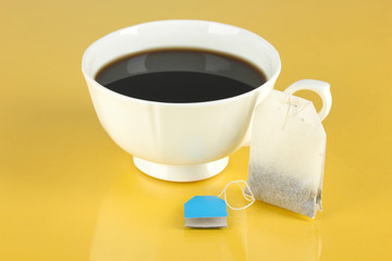 Cup of tea with tea bag on yellow background