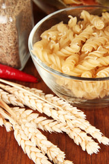 Different types of pasta, spices, tomatoes on a wooden table