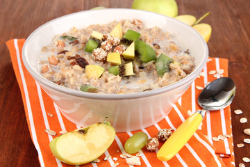 Useful oatmeal in bowl with fruit on wooden table close-up
