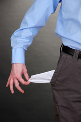 Business man showing his empty pocket, on grey background