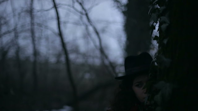 Girl hides behind a tree