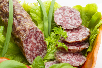 Ripe salami with salad, basil, onion and tomato