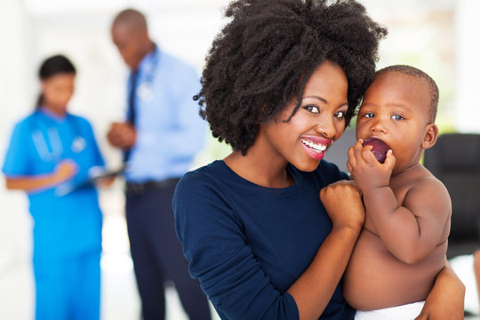 black mother holding her sick baby in doctor's office