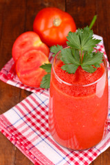 Glass of tomato juice on wooden table