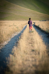 Obraz premium Kid walking alone outdoors. Castelluccio di Norcia, Italy.