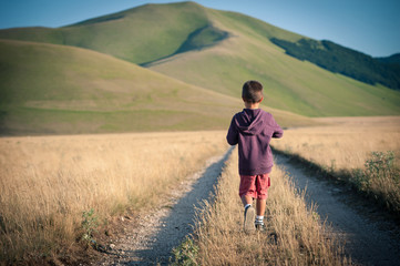 Kid walking alone outdoors. Castelluccio di Norcia, Italy. © pio3