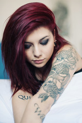 Sensual portrait of beautiful girl with tattoo lying on bed.