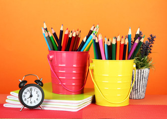 Colorful pencils in two pails with copybooks