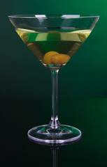 Martini glass with olives on dark green background