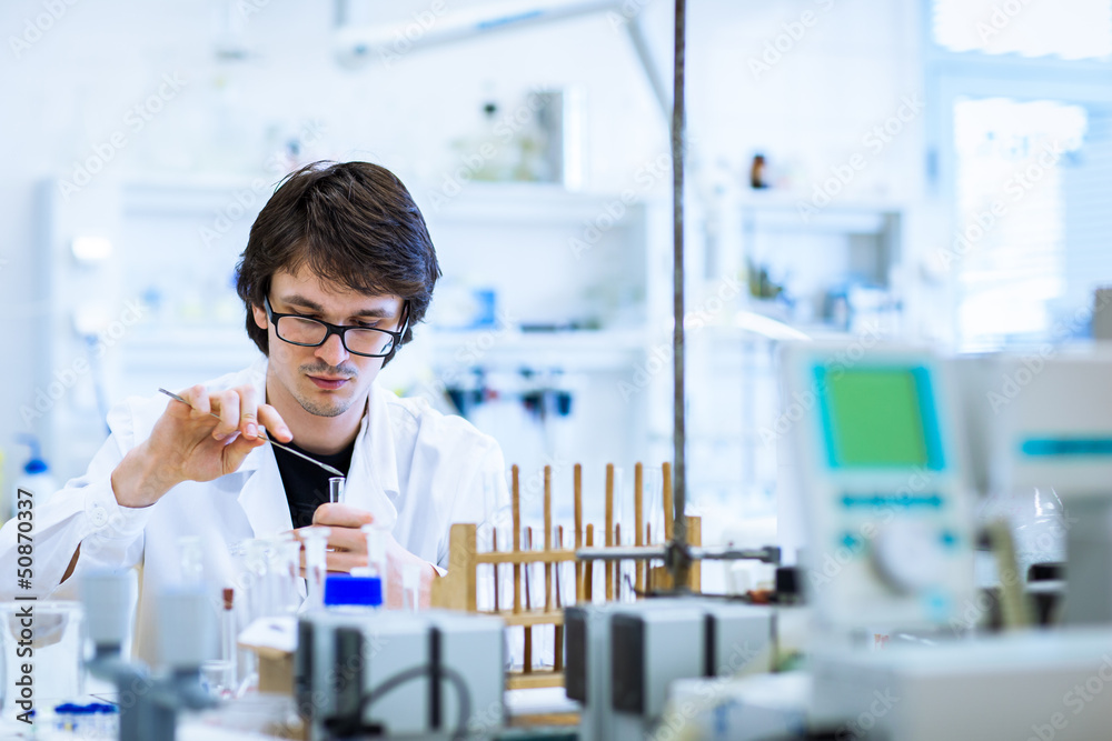 Wall mural young male researcher carrying out scientific research in a lab