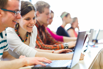 College students sitting in a classroom, using laptop computers