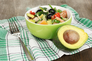 Tasty avocado salad in bowl  on wooden table close-up