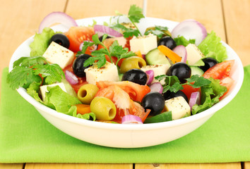 Fresh salad in plate on wooden table