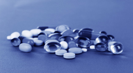 Assortment of pills, tablets and capsules in blue light