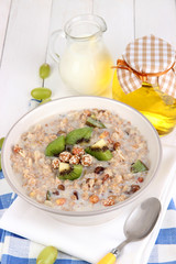 Useful oatmeal in bowl with fruit on wooden table close-up