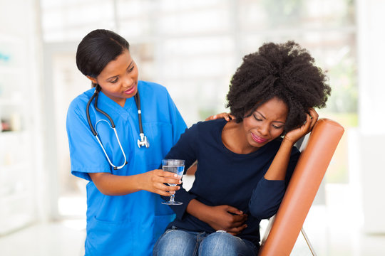 Caring African American Nurse Offering Sick Patient Water