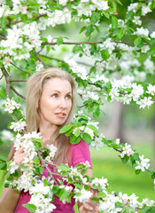 young attractive woman standing near the blossoming apple tree 