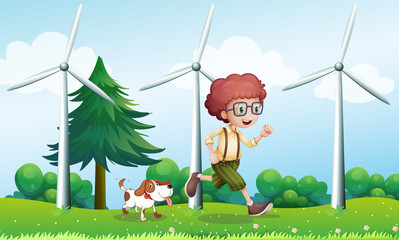 A boy running with a dog near the three windmills