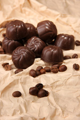 Chocolate candies and coffee beans, on beige paper background