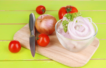 Onion cut with rings in bowl on wooden table close-up