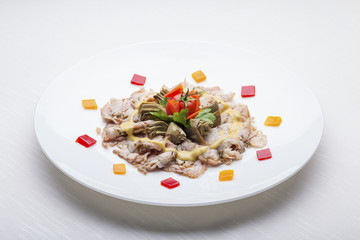 Plate of sliced rabbit ham with marinated artichokes