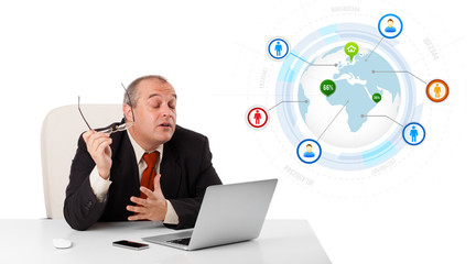 businessman sitting at desk and looking laptop with globe and so