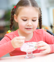 Little girl is eating ice-cream in parlor