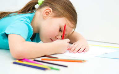 Little girl is drawing using pencils