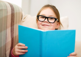 Little girl is reading a book