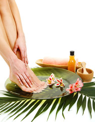 Female feet in spa bowl with water, isolated on white