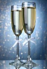 Two glasses of champagne on bright background with lights