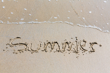 Summer handwritten inscription in sand on a beach