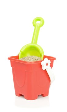 A toy bucket and spade with sand on a white background