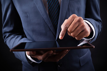 Businessman working on a digital tablet against black backgroun