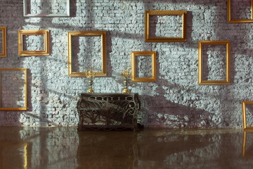 Empty picture frames on brick wall and forged chest
