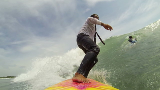 Cheerful businessman on surf board rides a tropical ocean wave