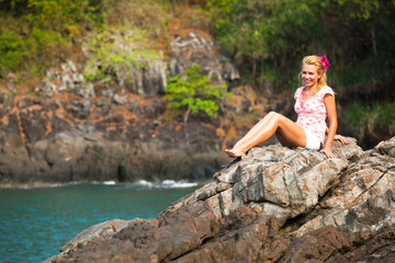 Girl is sitting on the rocks at the seaside.