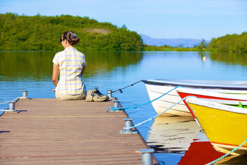 Fototapeta premium Woman sitting on a pier