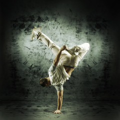 Fototapeta na wymiar Sporty modern dancer over the dramatic background in sepia style