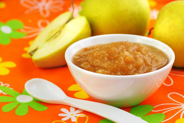Homemade apple puree in a bowl on colorful tablecloth